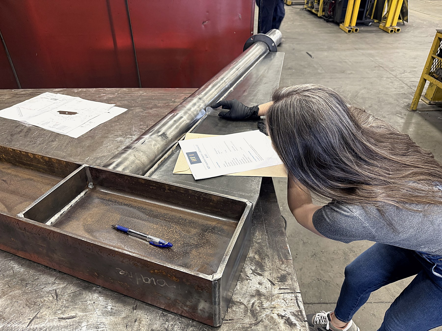 Noble Testing inspector examining a weld with a gauge in a fabrication shop